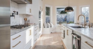 Modern kitchen remodel featuring white cabinetry, gold hardware, marble countertops, and a spacious island with updated fixtures and lighting.