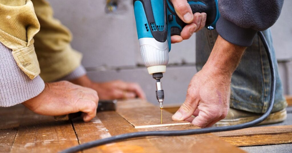 Handyman using a power drill to fasten wood during a home repair project