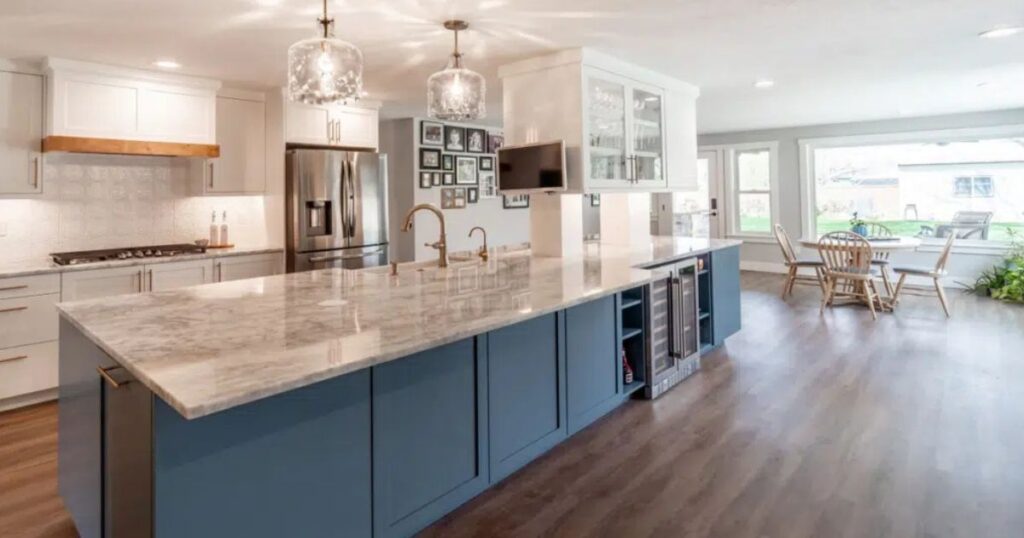 Modern Boise kitchen with white perimeter cabinets, a large blue island, quartz countertop, pendant lights, and open dining area.