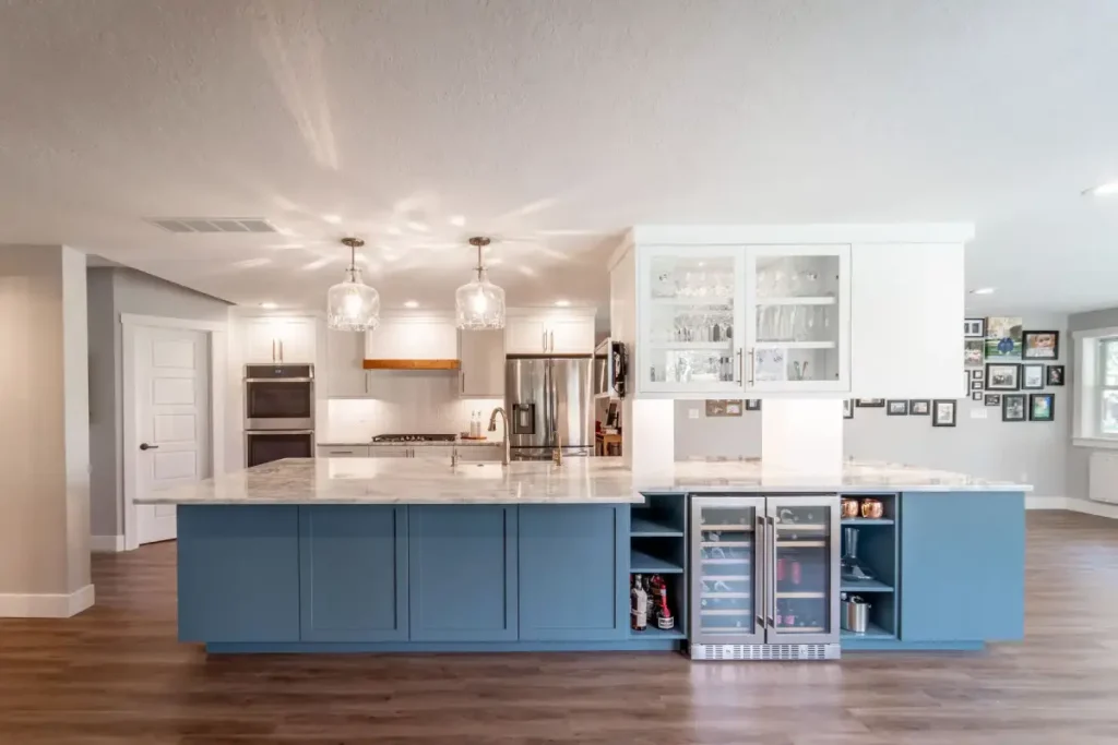 Boise kitchen remodel featuring large blue island with marble countertops, pendant lighting, stainless steel appliances, and built-in wine cooler by Renaissance Remodeling